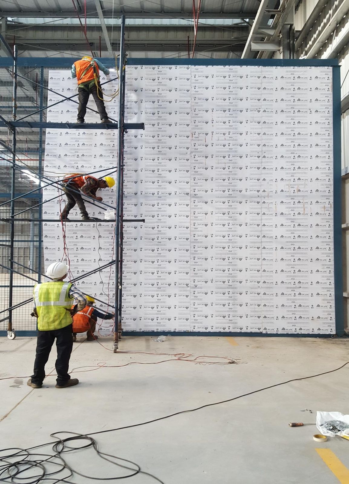 Site team installing tall panel partitions for cabins inside a warehouse