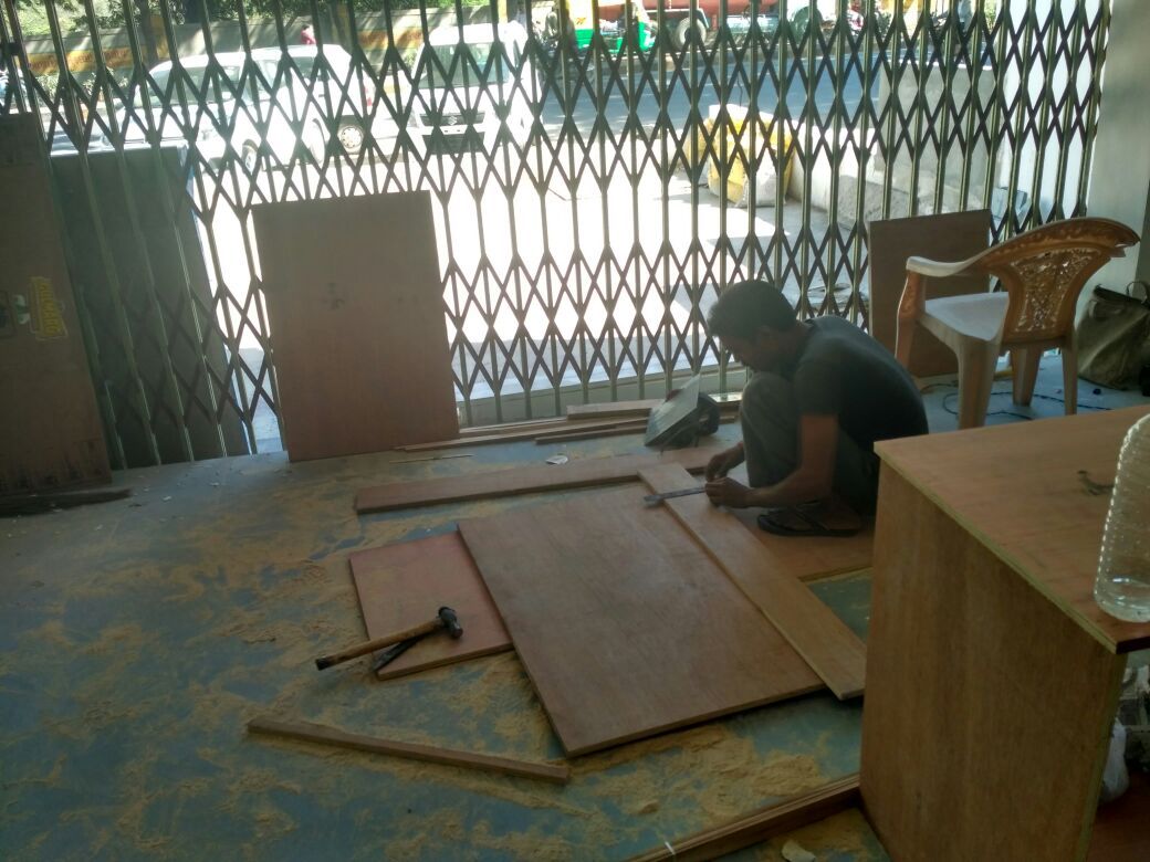 Carpenter cutting plywood sheets on the floor of the FedEx Jamnagar site