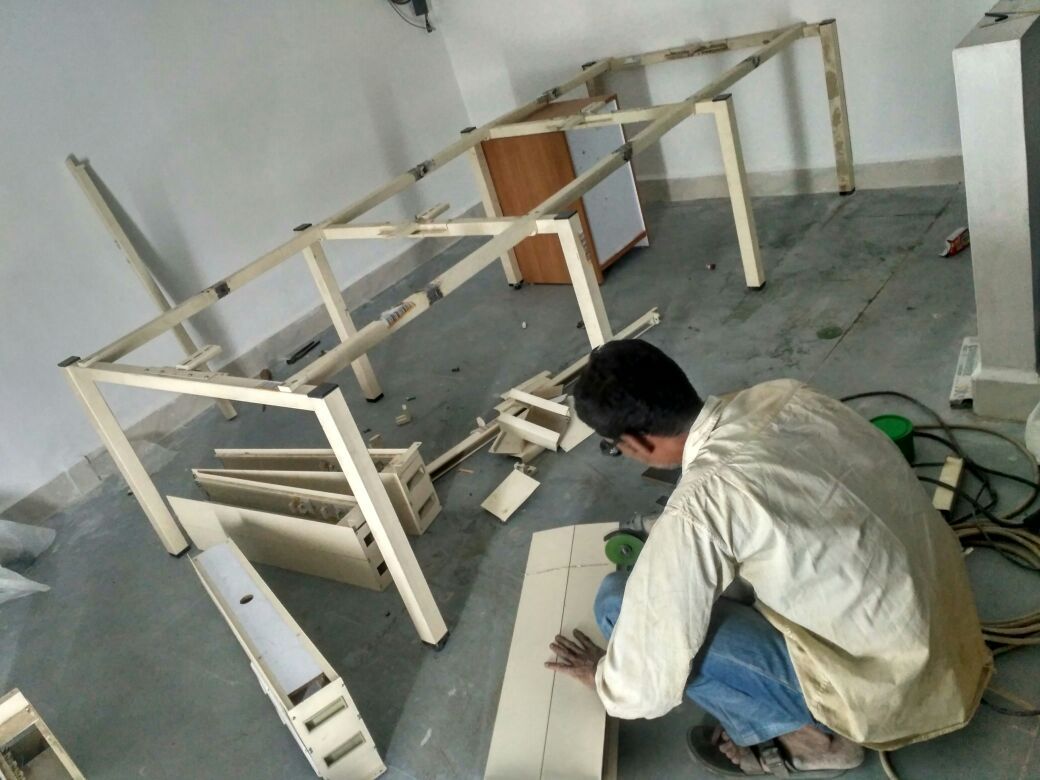 Worker assembling workstation frames inside the FedEx Jamnagar office