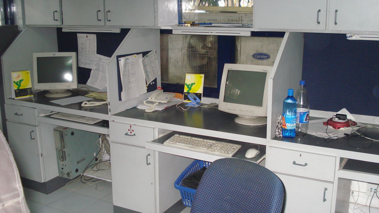 Workstations with overhead storage cabinets in use at a Pune office
