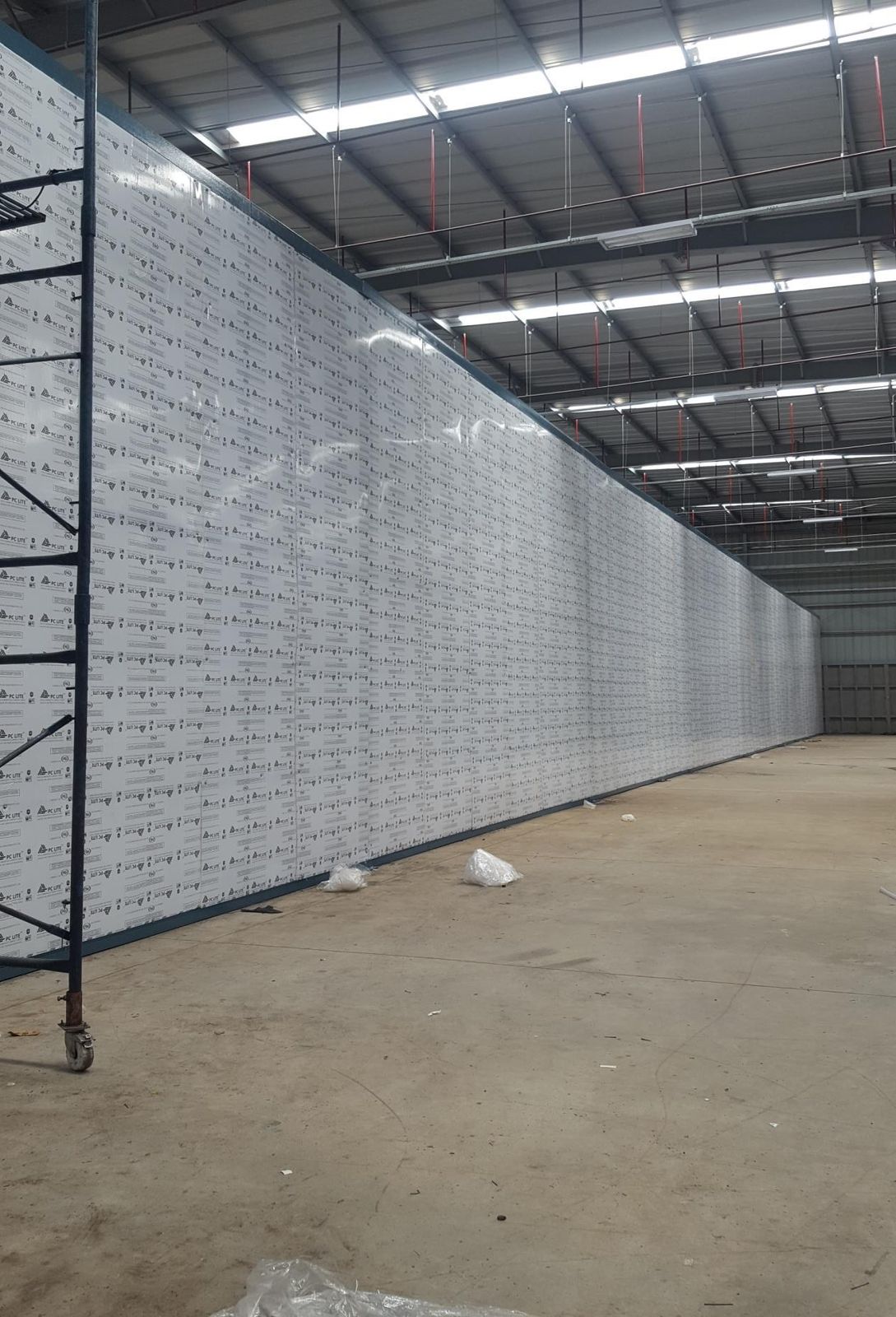 Full-height lined partition wall running the length of a warehouse bay